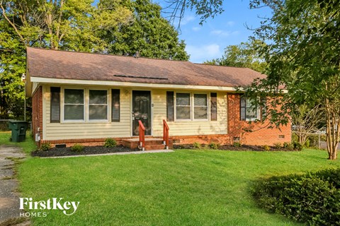 a small brick house with a lawn and a tree