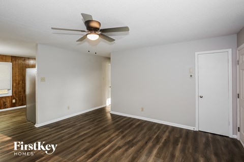 a living room with white walls and a ceiling fan