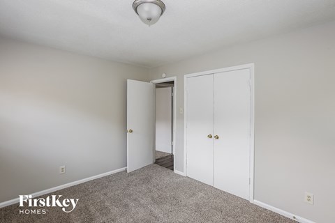 a bedroom with white closets and carpet and a door to a hallway