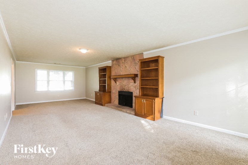 A spacious living room with a fireplace and built-in bookshelves.