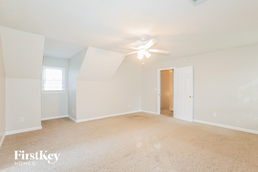 A spacious room with a ceiling fan and carpeted floor.