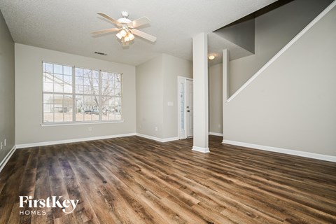 A spacious room with wooden floors and a ceiling fan.