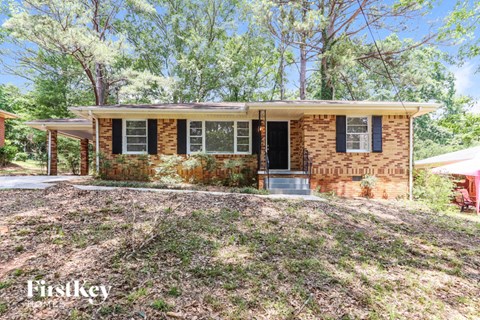 a small brick house with a front yard and trees