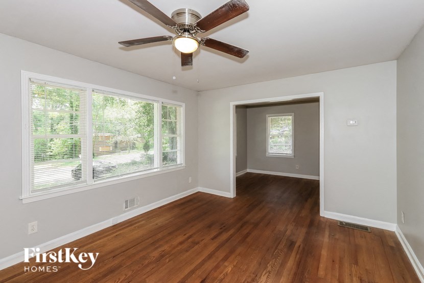 an empty living room with wood floors and a ceiling fan