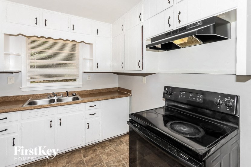 a kitchen with white cabinets and black appliances and a sink