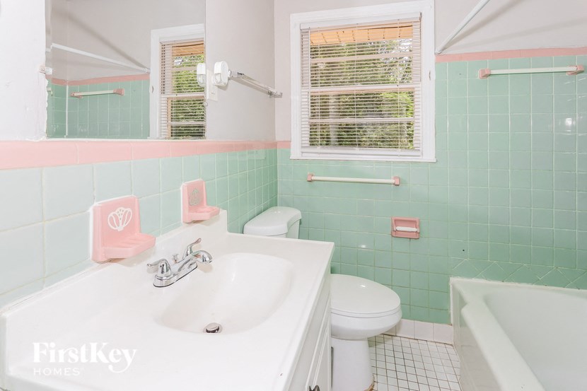 a bathroom with mint green tiles and a white sink and toilet