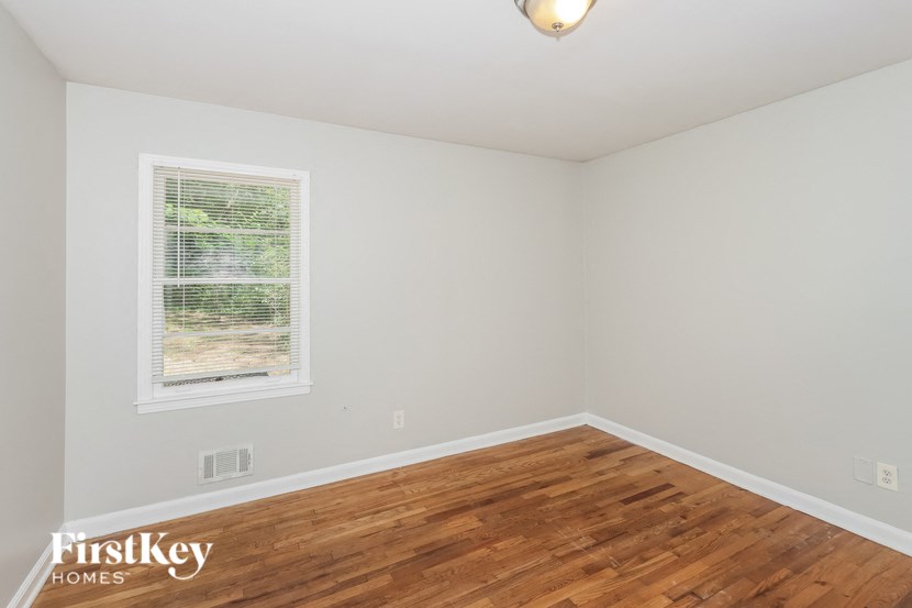 a bedroom with wood floors and white walls and a window