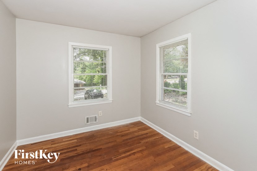 a bedroom with a hard wood floor and two windows