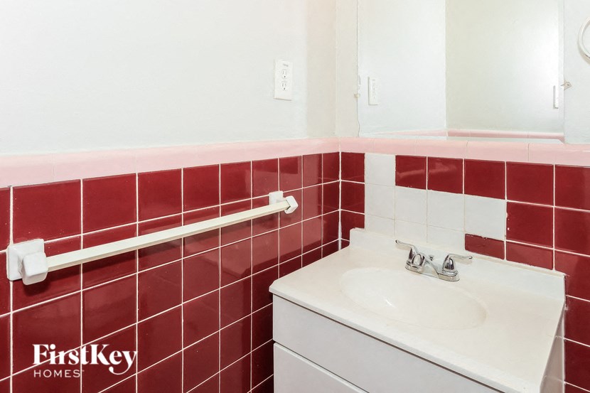 a bathroom with red tile and a white sink