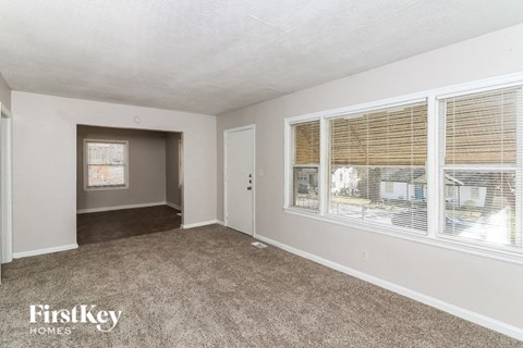 A room with a carpeted floor and a window with blinds.