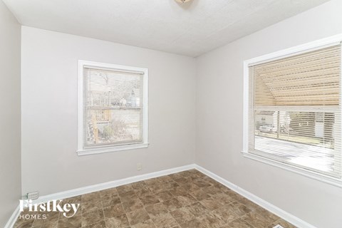 A room with a window covered by blinds and a picture on the wall.