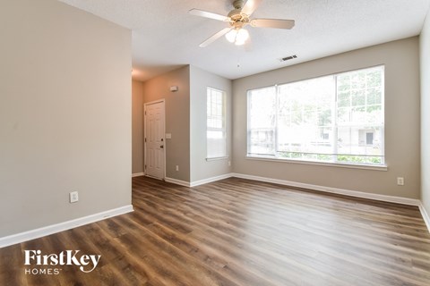 A spacious room with a ceiling fan and wooden flooring.