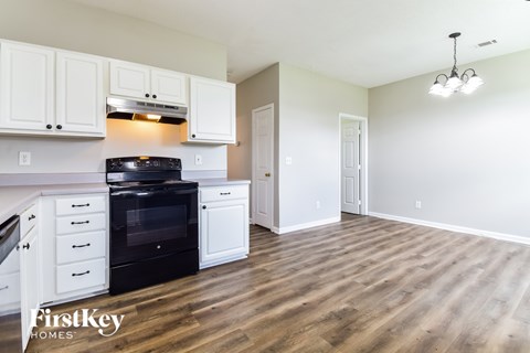 A kitchen with white cabinets and a black stove top oven.