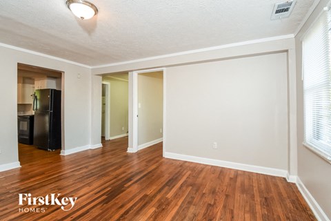 the living room and dining room of an empty house with wood flooring