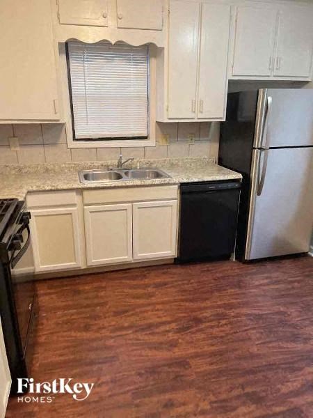 A kitchen with wooden floors and white cabinets.