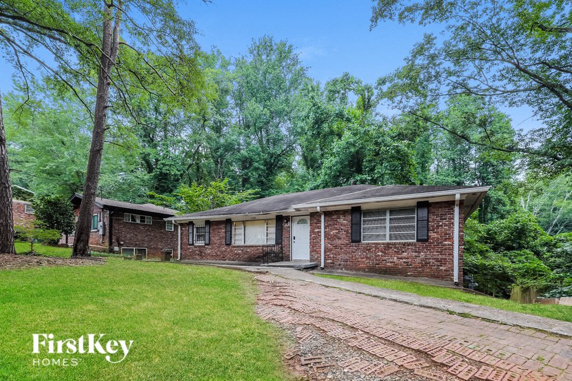 a brick house with a driveway and a yard with trees