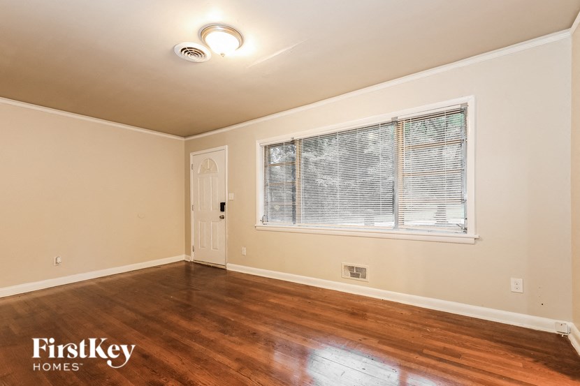 an empty living room with a large window and wooden floors