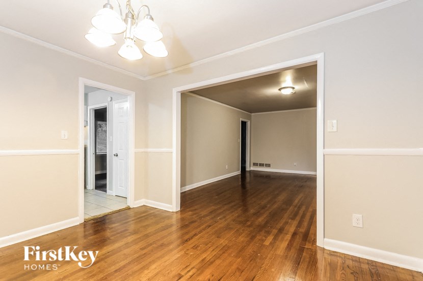 an empty living room with wood flooring and a door to a hallway