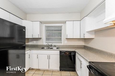 a kitchen with white cabinets and black appliances and a sink