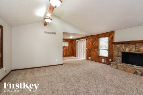 the living room has a stone fireplace and carpeted flooring