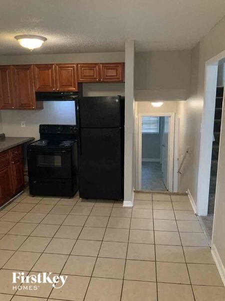 a kitchen with a black refrigerator and wooden cabinets