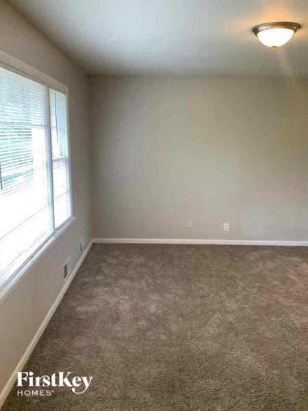 an empty living room with a large window and carpet