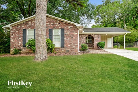 a small brick house with a lawn and a tree