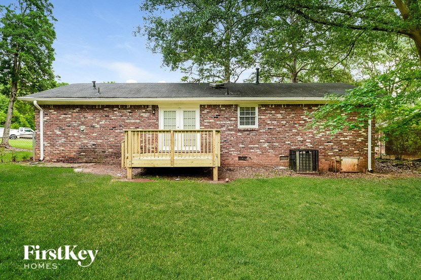 a backyard deck in front of a brick house