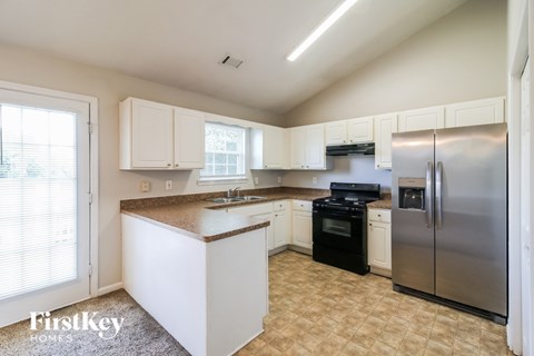 A kitchen with white cabinets and a stainless steel refrigerator.