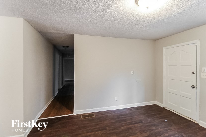 the living room of an empty house with a wooden floor and a white door