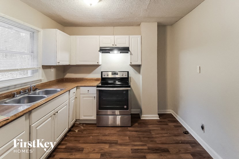 a kitchen with white cabinets and a stove and a sink