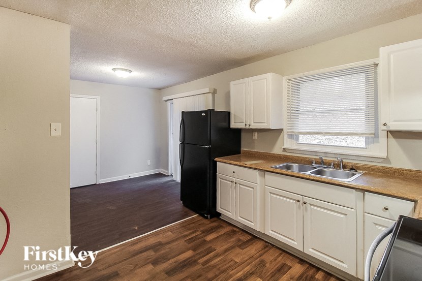 a kitchen with white cabinets and a black refrigerator