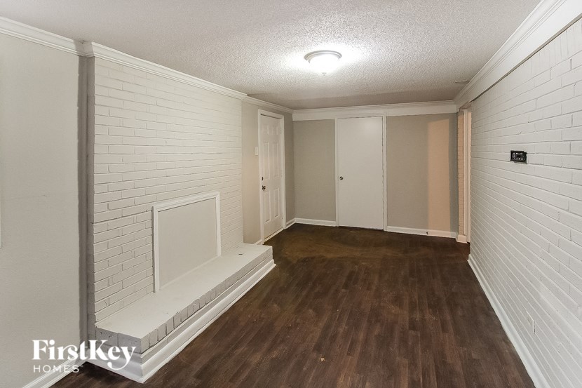 an empty living room with a white brick wall and wood flooring