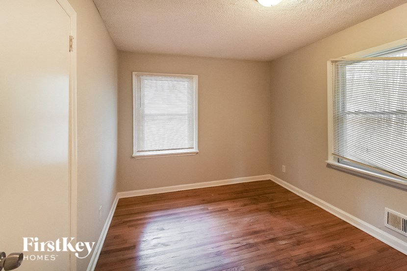 a bedroom with a hard wood floor and two windows