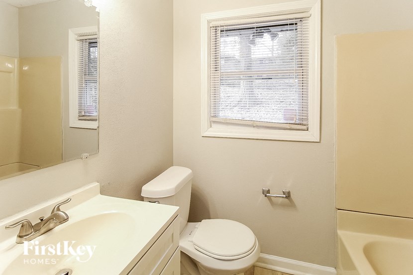 a bathroom with a toilet and a sink and a window
