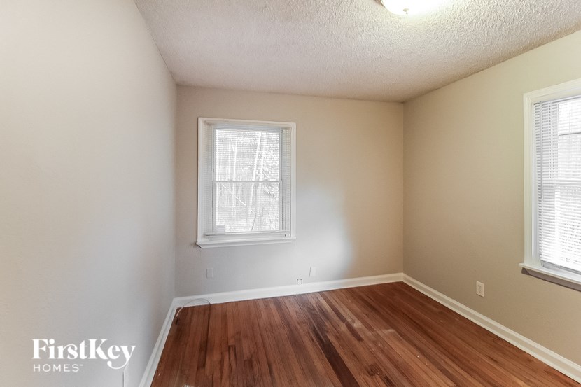 a bedroom with a hard wood floor and two windows