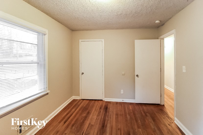 a bedroom with a wood floor and a window and a door