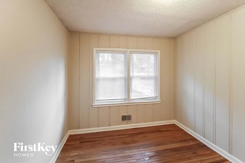 an empty room with a window and wooden floors