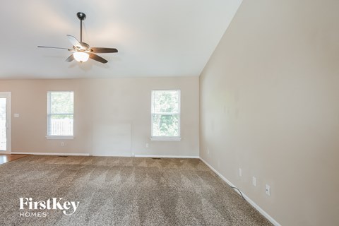 a living room with a ceiling fan and a carpet
