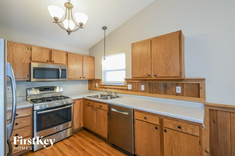 a kitchen with wooden cabinets and stainless steel appliances and a white counter top
