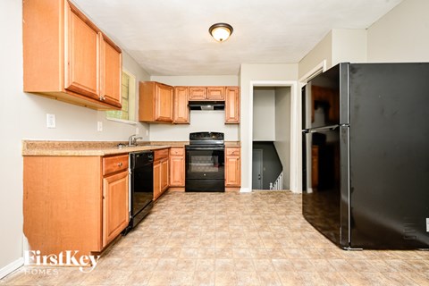 A kitchen with wooden cabinets and a black refrigerator.