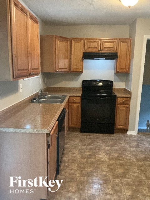 A kitchen with wooden cabinets and a black fridge.