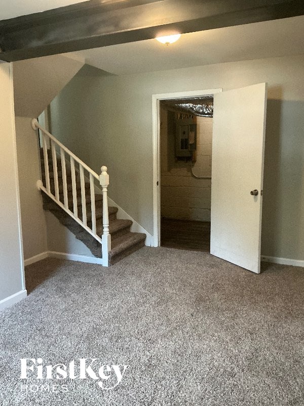 A room with a staircase and a door leading to another room.