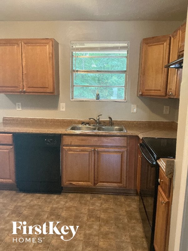 A kitchen with wooden cabinets and a black dishwasher.