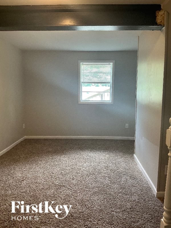 A room with a window and a carpeted floor.