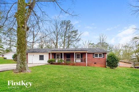 a small brick house with a yard and a tree