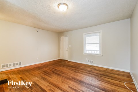 the living room of a house with a hardwood floor and a window
