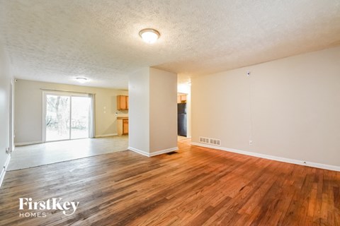 the living room and dining room of an empty house with wood flooring
