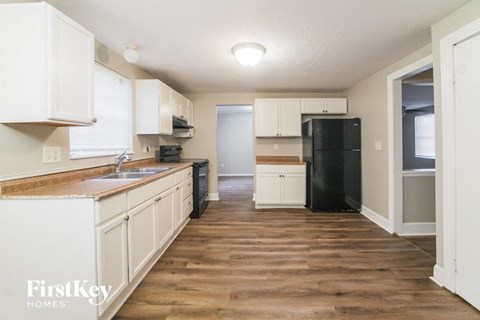 a kitchen with white cabinets and a black refrigerator