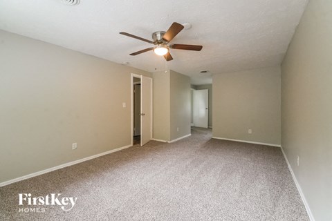 a spacious living room with carpet and a ceiling fan